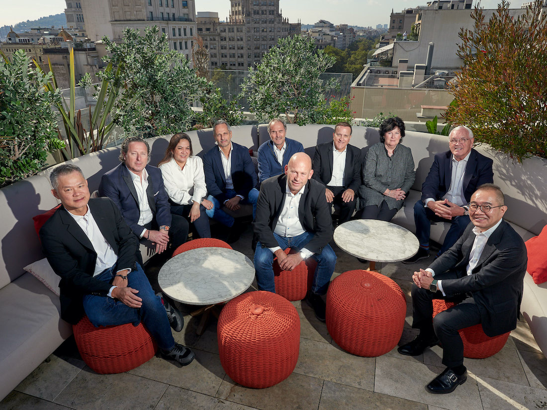 A group of people sat on a roof terrace in suits