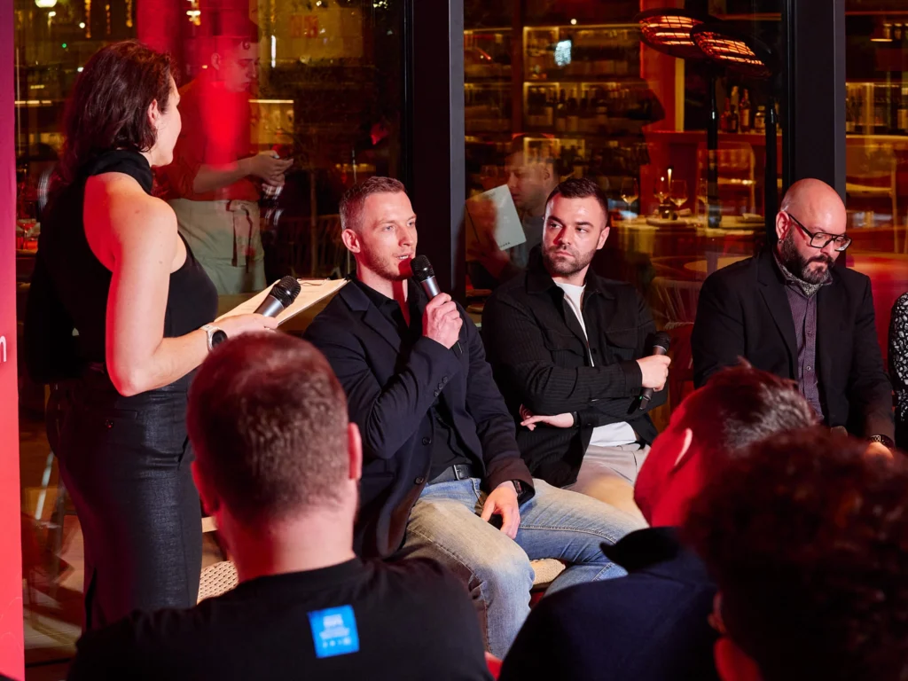 Odys host delivering a welcome speech, making eye contact with the camera, during the after-hours client event at Nuara in Barcelona