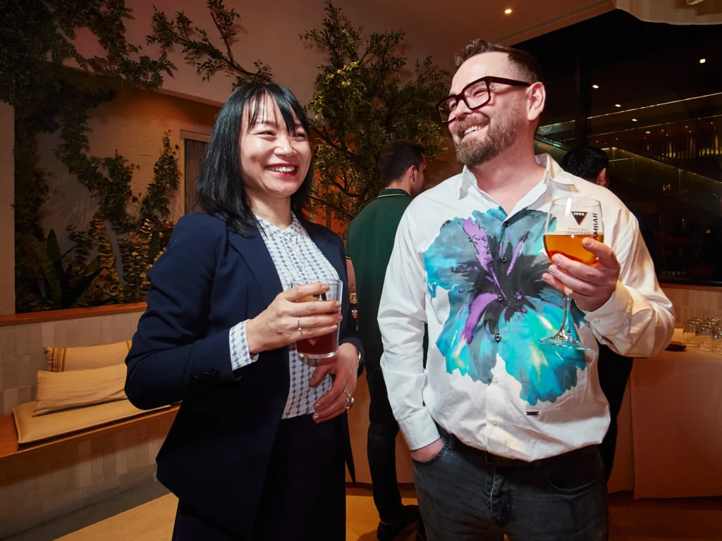 Two attendees engage in a conversation, one smiling directly at the camera, capturing the authentic connection fostered at the Barcelona corporate event.