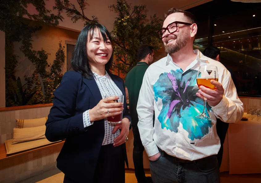 Two attendees engage in a conversation, one smiling directly at the camera, capturing the authentic connection fostered at the Barcelona corporate event.