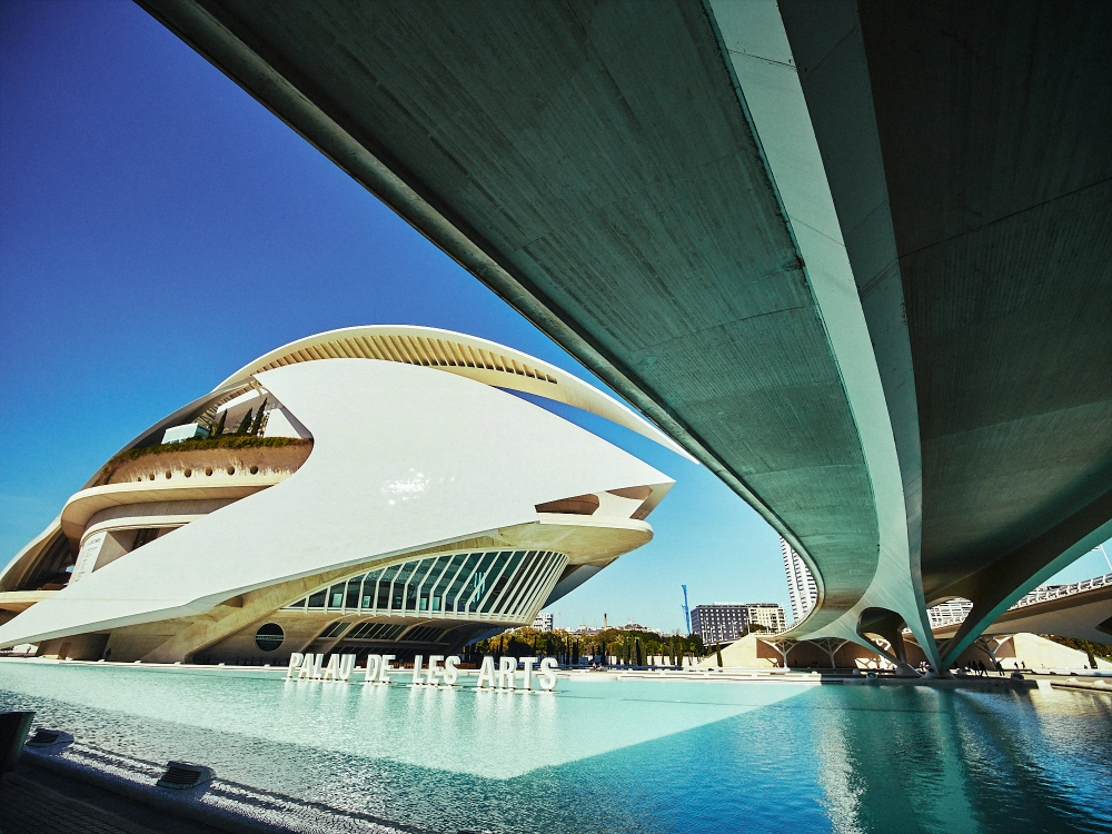 Modern curved architecture of Valencia’s City of Arts and Sciences reflected in water on a sunny day.