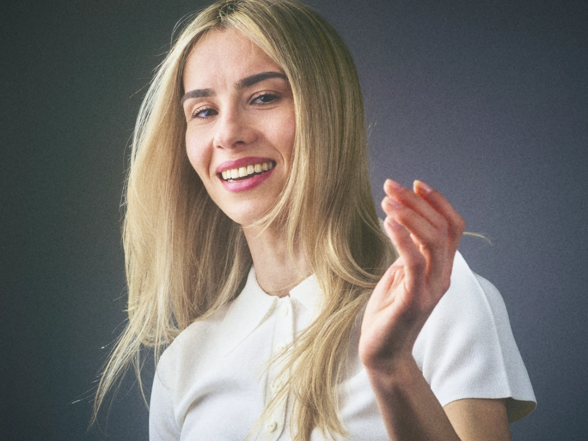 An Image of a young blonde woman shot in a studio with Godox flash, she is happy and there is movement in the image