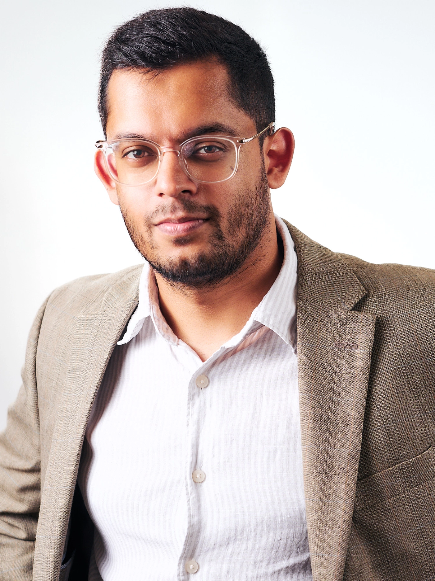 A south Asian man casual in. jacket against a white background portrait