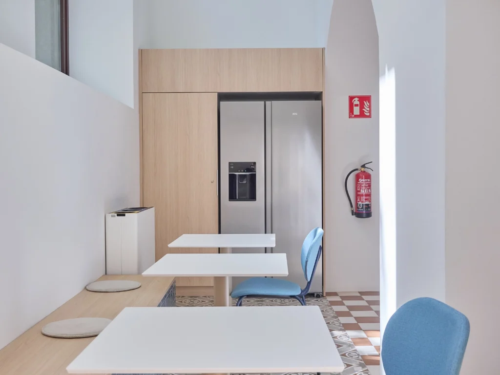 A stylish breakout area connected to the main kitchen, offering a relaxed dining space with contemporary furnishings for members.