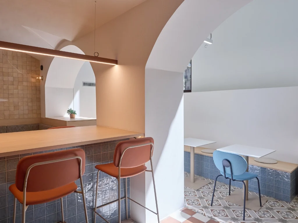 A vibrant communal kitchen serving as the social heart of an upscale Barcelona coworking space, designed for casual networking and breaks.