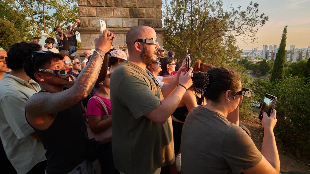 People in Profile wearing solar eclipse glasses on Montjuic