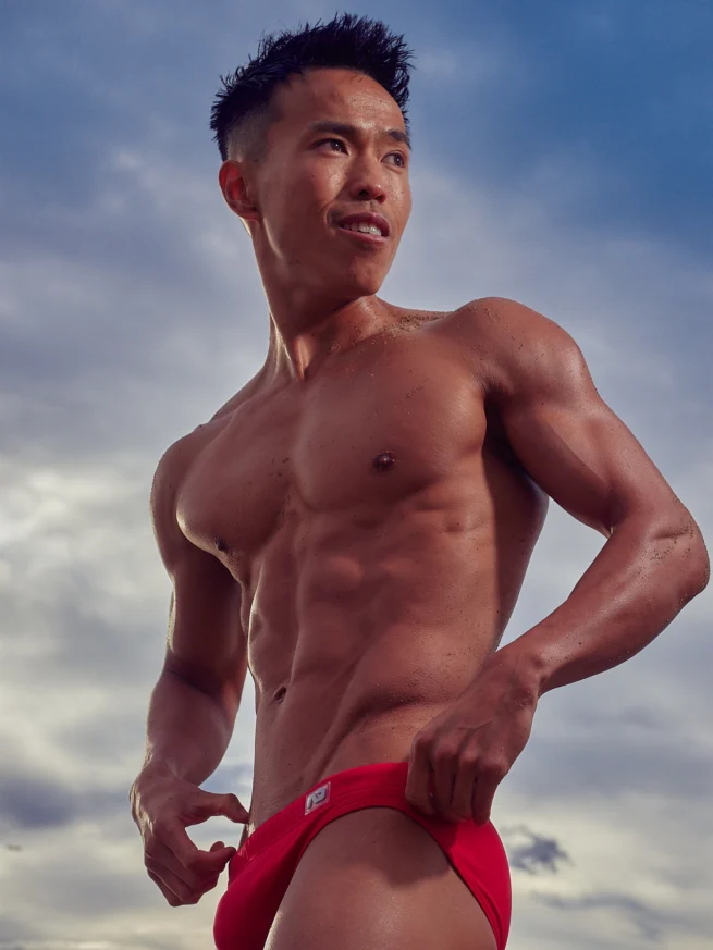 Asian man topless and very toned at sunrise on the beach