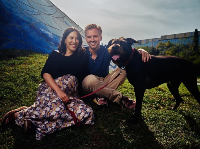 2 people and a dog sat smiling at the camera, yes the dog too