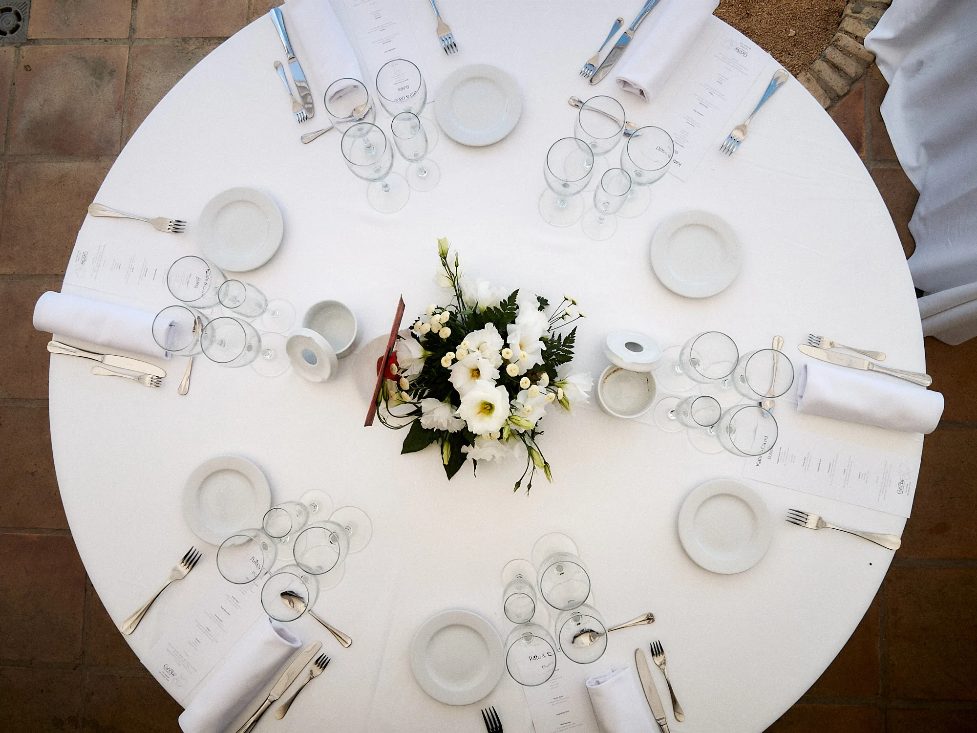 Overhead view of a round wedding reception table set with white flowers at Can Tallada