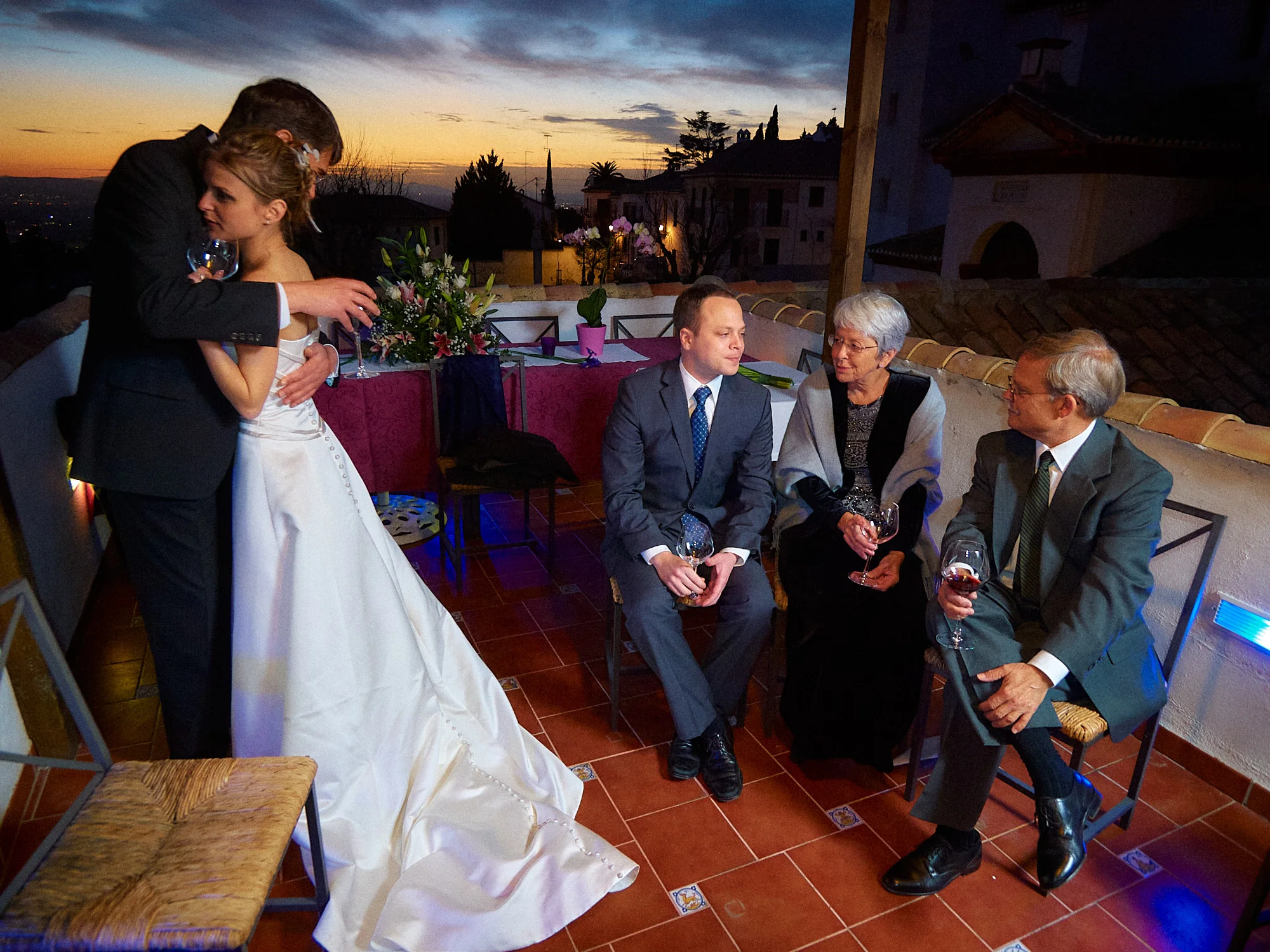 Drea & Brian Granada Wedding – Terrace Reception Drea and Brian with guests on a Granada terrace during the wedding reception at dusk