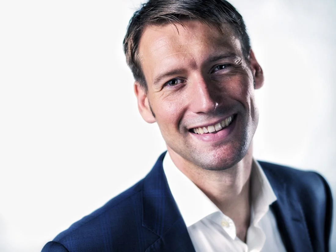 Smiling man in a navy suit against a light background