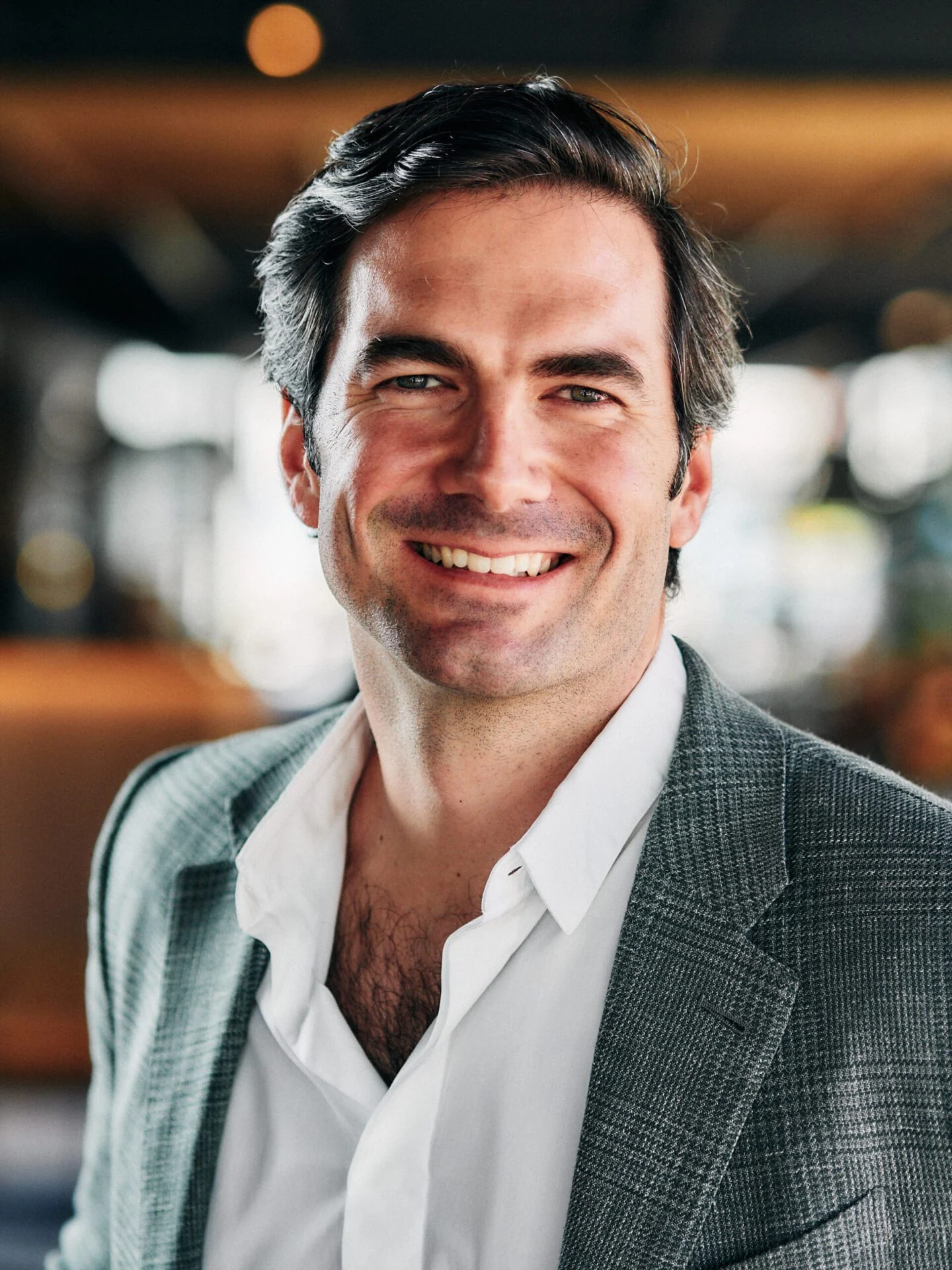 Smiling man in a checked blazer, photographed indoors