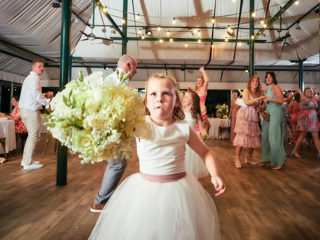 Young wedding guest dancing with a bouquet during Jade and Aidhan’s reception