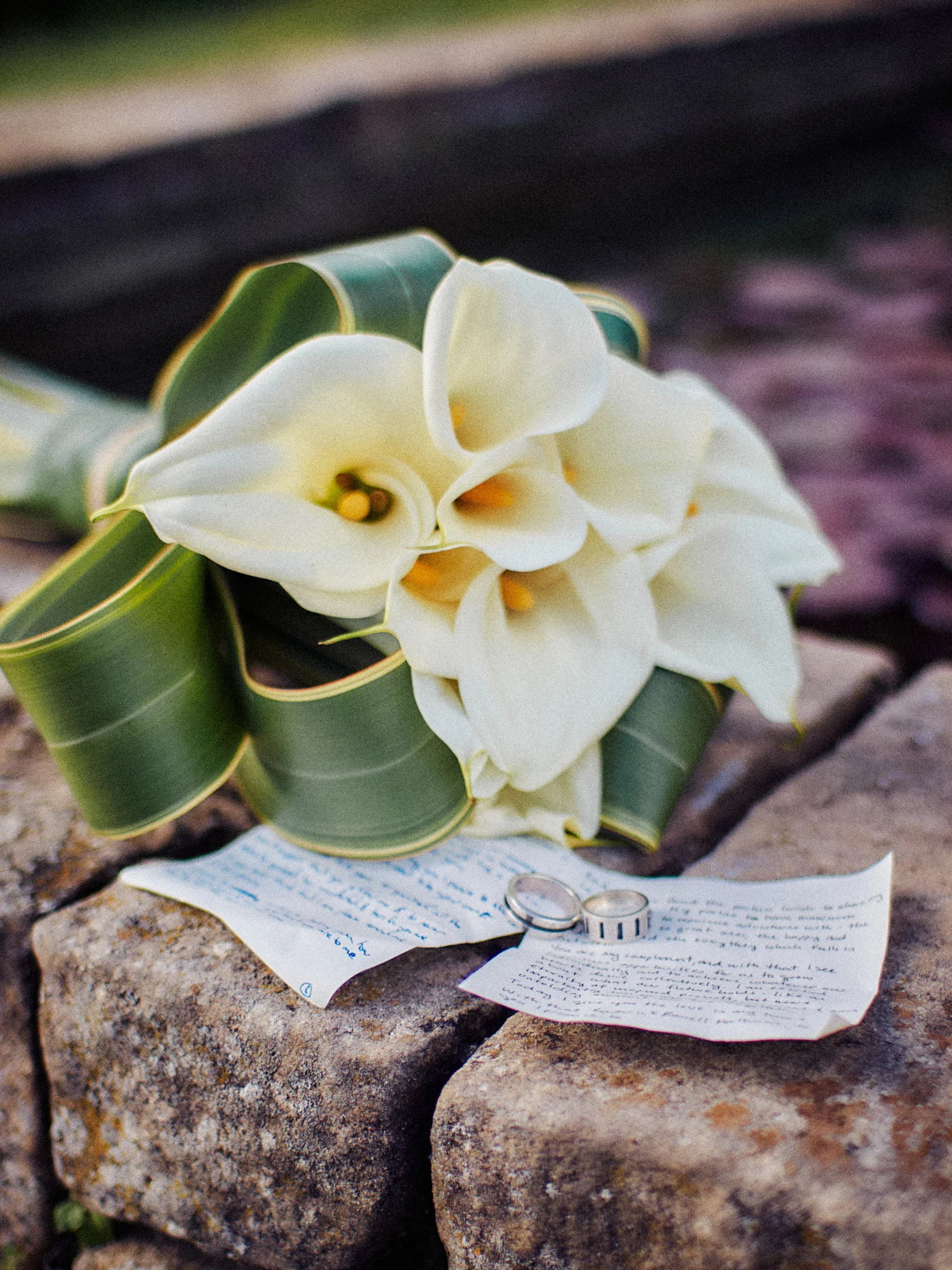 Calla lily bouquet and handwritten wedding vows on a stone wall